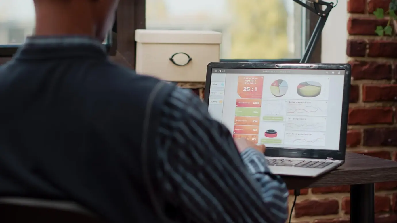 Ассистент по продажам планирует бизнес-диаграммы на ноутбуке, работая в офисе компании с управлением электронной коммерцией и онлайн‑покупками. Менеджер использует статистику для разработки креативного проекта.